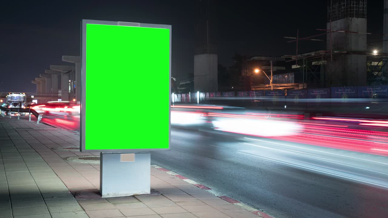 Time lapse. Cartellone pubblicitario con schermo verde, situato su una strada trafficata. Le auto si muovono la sera.