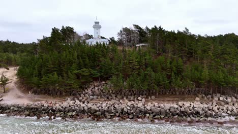 Lighthouse-With-Pine-Trees-And-Concrete-Blocks-In-Baltic-Sea-In-Uzava,-Latvia