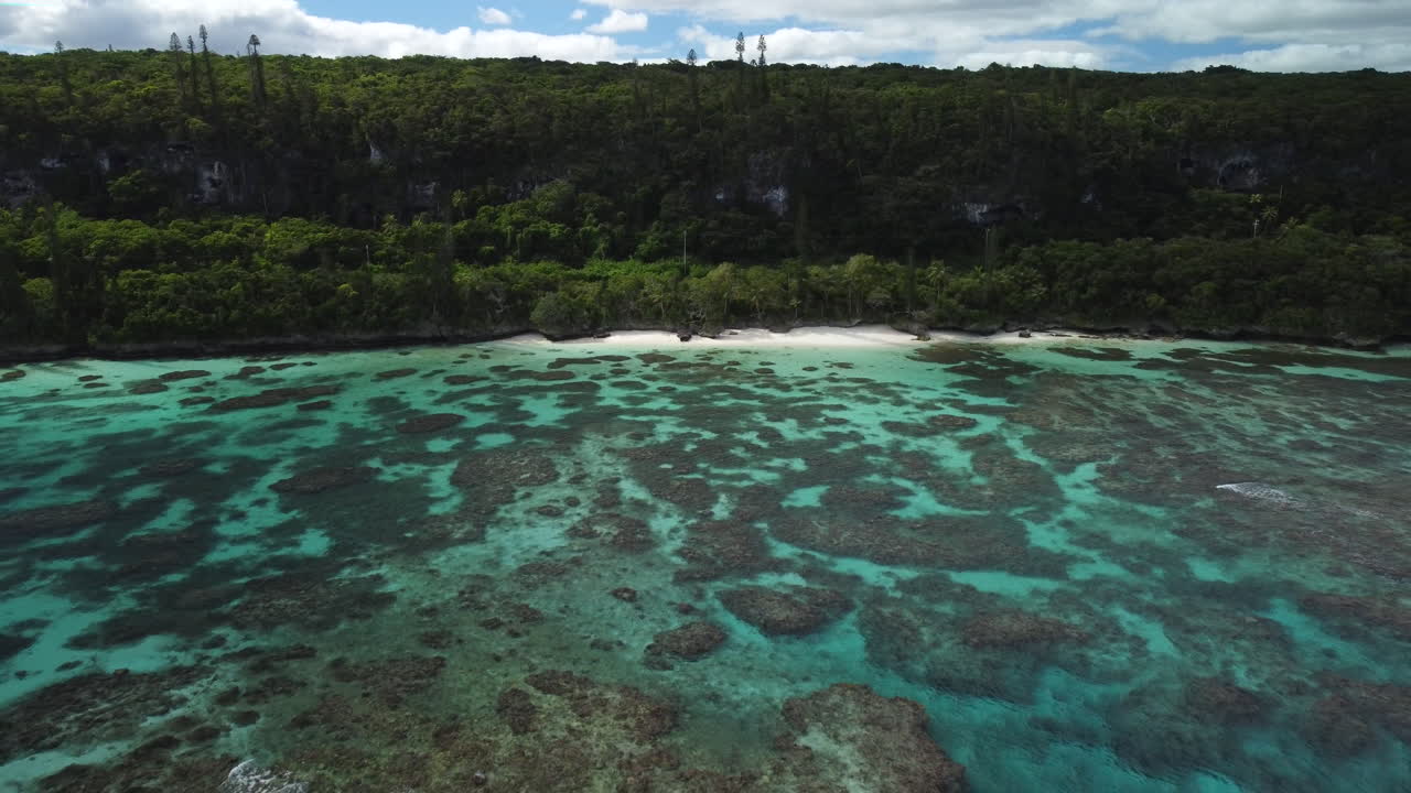 Ripresa aerea in allontanamento da una spiaggia mozzafiato e acqua cristallina sull'Isola di Maré, Nuova Caledonia.