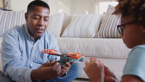 Pre-teen-girl-and-grandad-sitting-on-the-floor-in-living-room-constructing-a-model-robot,-close-up