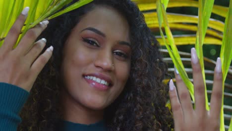 a girl drops palm branches over her face while smiling