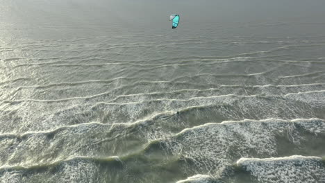 kite surfer close to the beach, riding the wind with his kite, drone footage