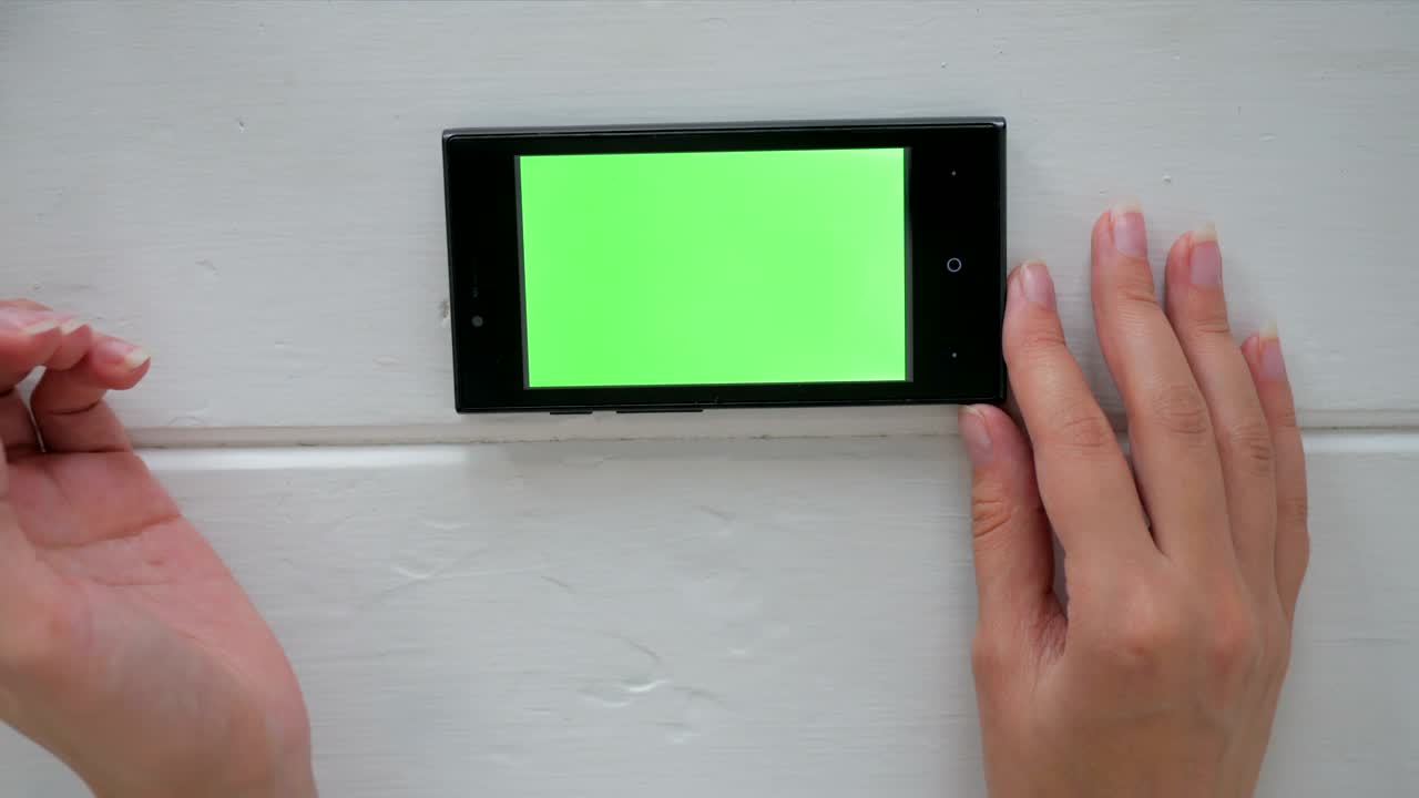 초록색 화면의 스마트폰을 사용하는 여성