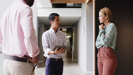 discussing project details, business team using tablet in modern office hallway