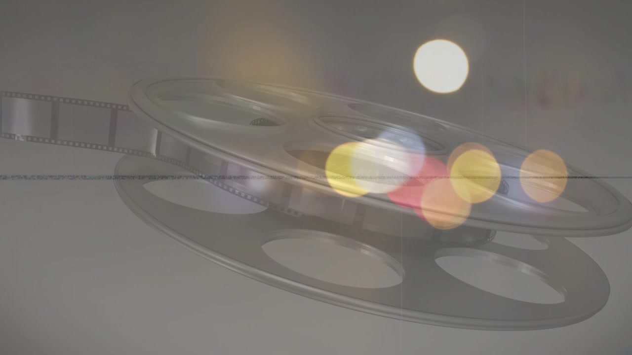 Metallfilmspole i avspilling vipper og roterer mens farget bokeh skifter for et filmatisk overlegg.