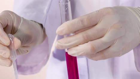 a scientist uses a pipette to add liquid to a test tube, observing color changes.
