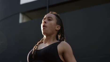 Front-view-of-young-African-American-woman-holding-her-hair-up-in-the-city-4k