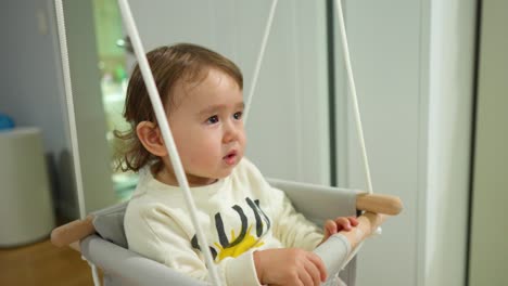 hermosa niña en el columpio de la puerta interior - primer plano de la cara en cámara lenta