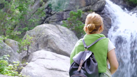 Unrecognizable-woman-standing-near-cascade-in-highlands