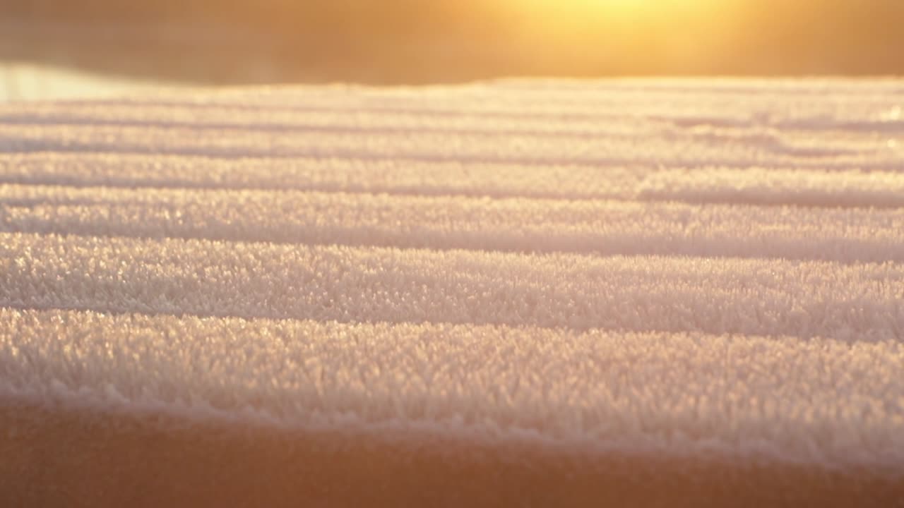 Smooth crane showing a frozen surface and the steam that comes out in the early morning sun. In the background a beautiful sunrise
