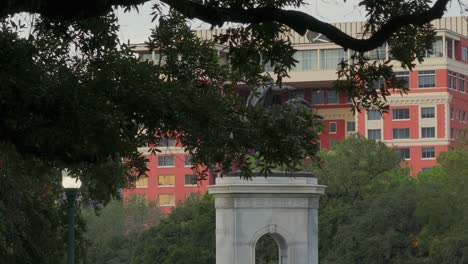 equestrian statue of sam houston in a park with a large red building in the background