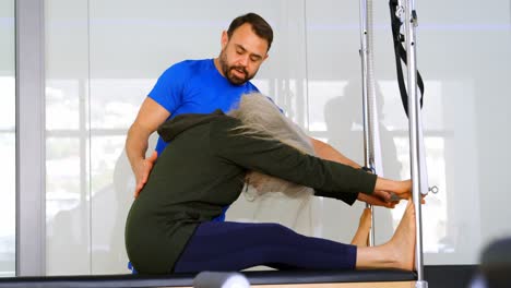 entrenador ayudando a una mujer mayor en la realización de yoga 4k