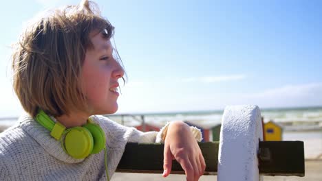 chica adolescente con auriculares mirando la playa 4k
