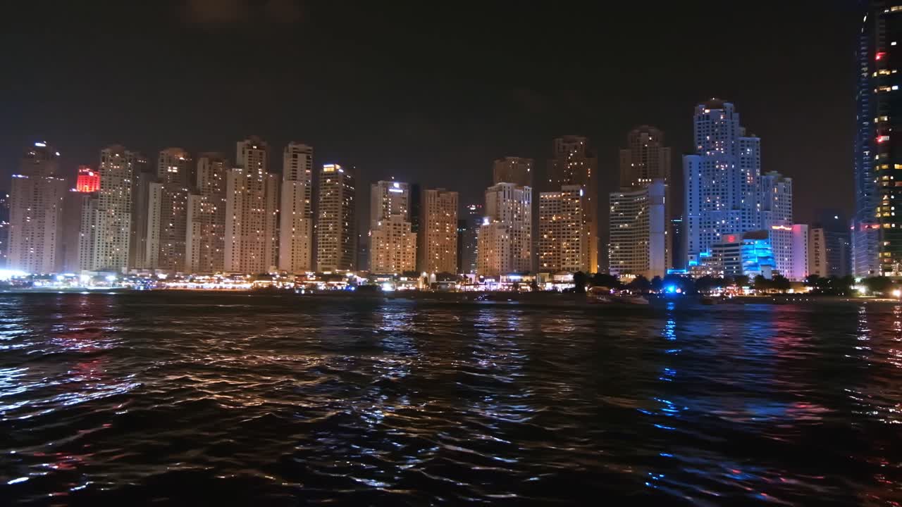Scenic shot of the coastline at night near the beautiful buildings in Dubai, United Arab Emirates