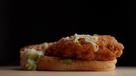 primer plano de la mano recogiendo pan de hamburguesa de pollo frito con lechuga y aderezo