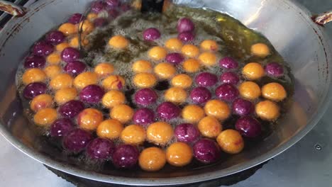 cocinar huevos de caramelo de codorniz o huevos de tortuga dulces en una sartén grande con aceite caliente, bocadillo tradicional tailandés hecho de harina de yuca (almidón de tapioca) y patata dulce en el mercado. imágenes de 4k.