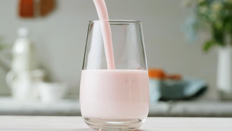 pouring strawberry yogurt into a glass