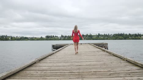 blonde model woman in red dress walking on a pier