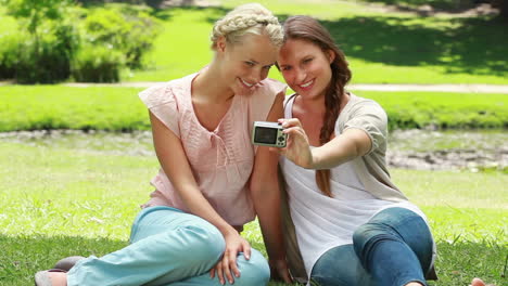 Two-women-pose-for-a-photo-and-then-look-at-the-result-and-then-look-at-the-camera