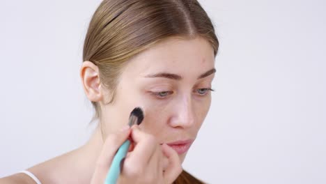 beautiful woman applying primer with brush