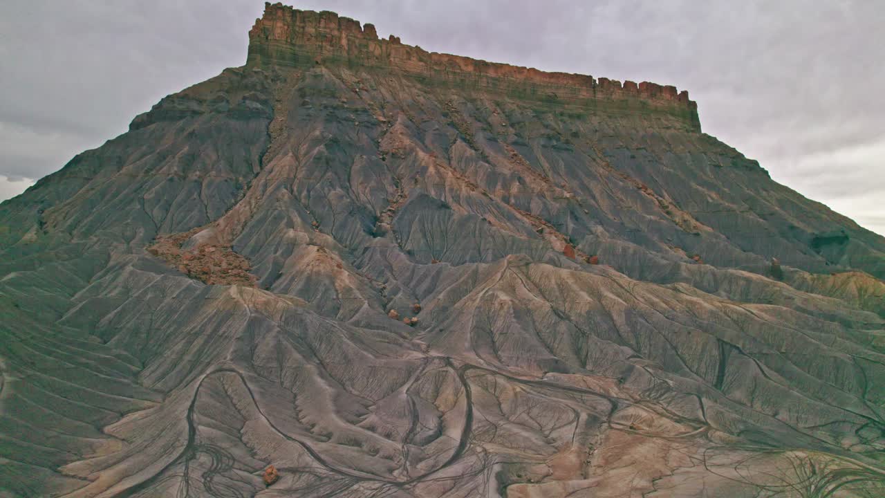 Epic pull back shot of 4K aerial footage over Utah’s Factory Butte, revealing striking ridgelines, banded rock layers, and the untamed grandeur of the desert wilderness.