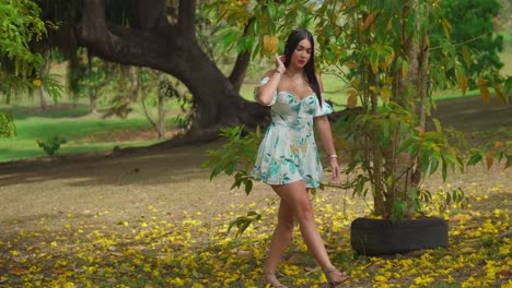 Chica-Latina-Caminando-En-El-Parque-Con-Un-Vestido-Corto-En-Otoño,-Cabello-Largo-Y-Negro-Que-Fluye