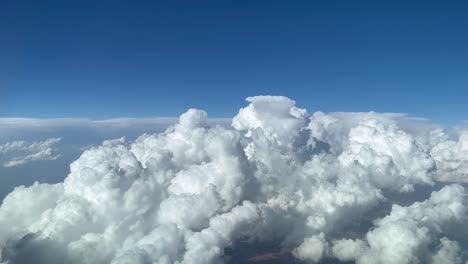 impresionante vista piloto desde la cabina de un jet evitando nubes de cúmulo tormentosas en un cielo azul profundo y desordenado