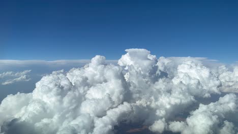 stunning pilot view from a jet cockpit avoiding stormy cumulus clouds in a messy and deep blue sky