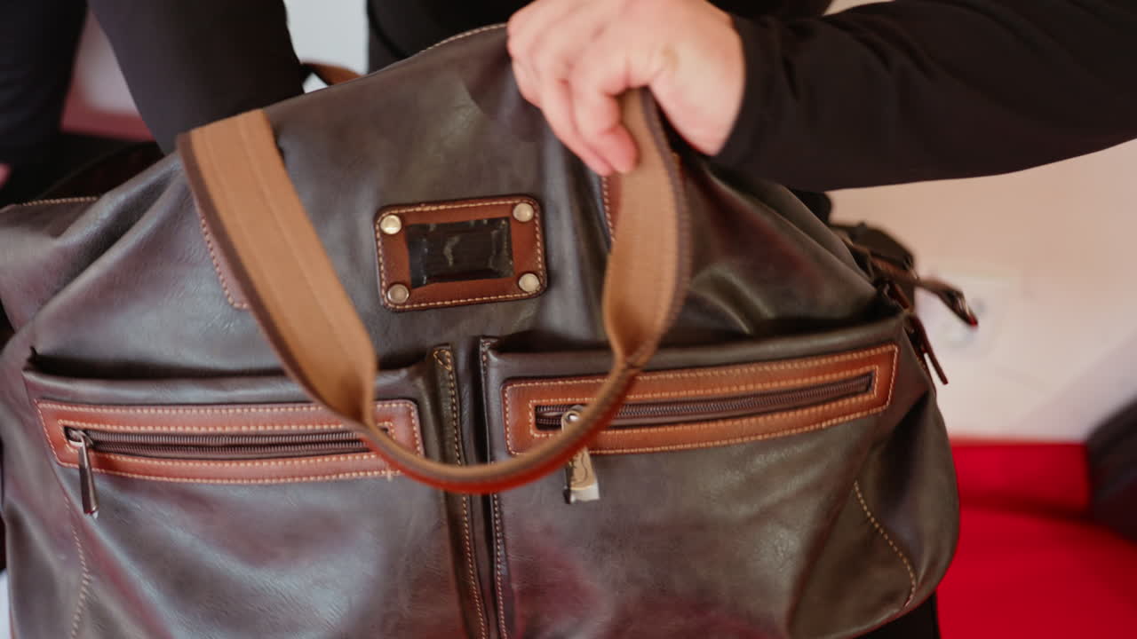 Closeup of man in black sportswear holding boxing gloves while sitting on red training mat indoors, symbolizing preparation, focus, determination, discipline, and readiness for physical activity