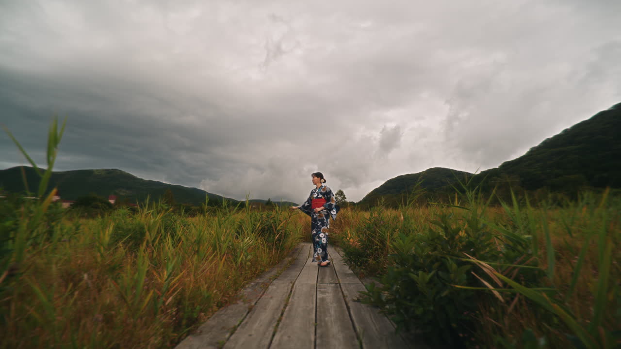 Woman in Kimono on a Path in a Grassy Landscape
