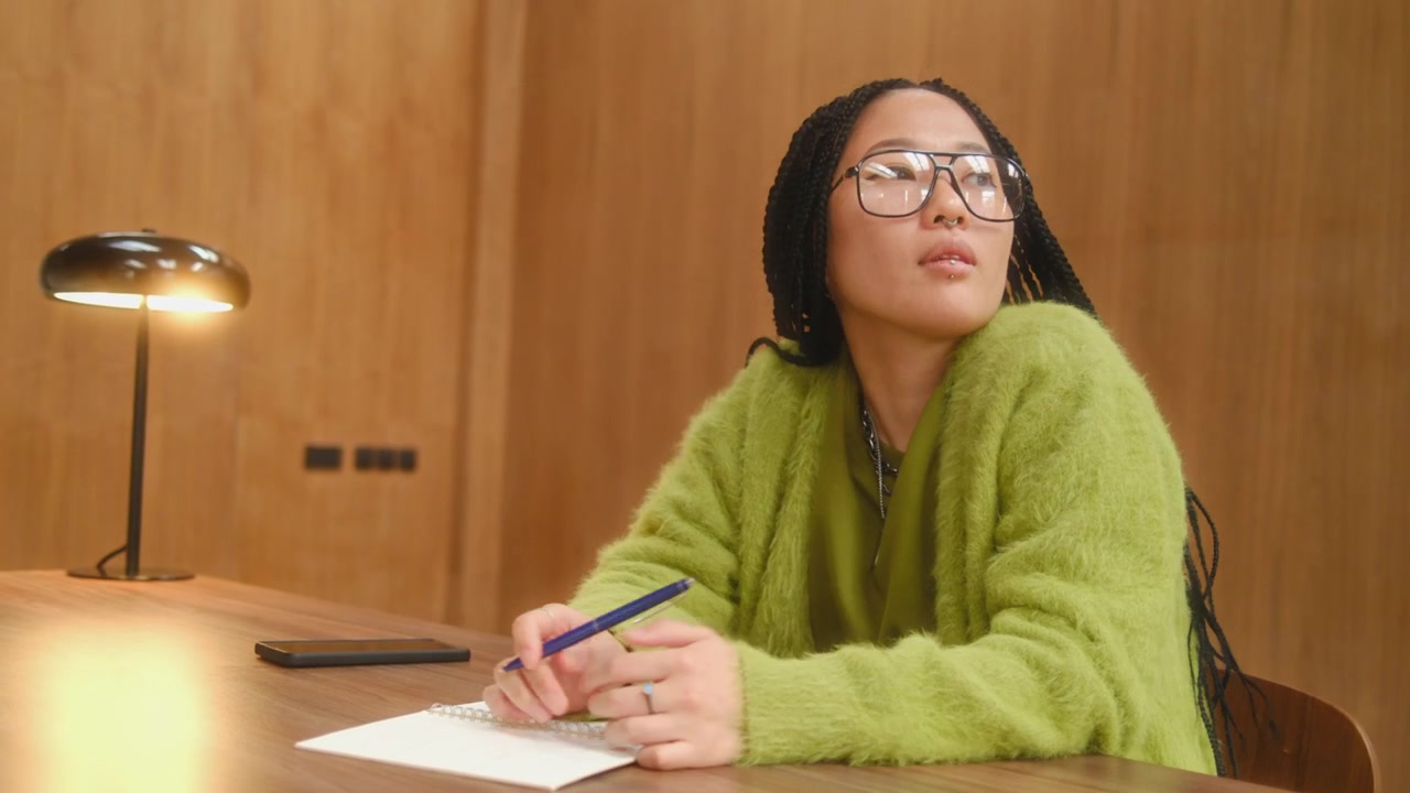 Giovane donna asiatica che pensa e scrive idee su un quaderno alla scrivania dell'ufficio