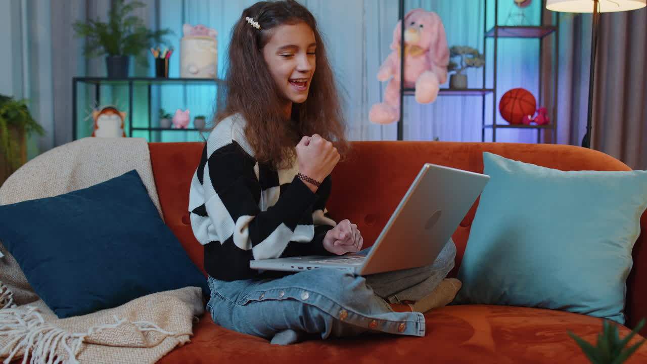 una joven asombrada usa una computadora portátil, recibe un mensaje de buenas noticias, conmocionada por la victoria, celebra la victoria