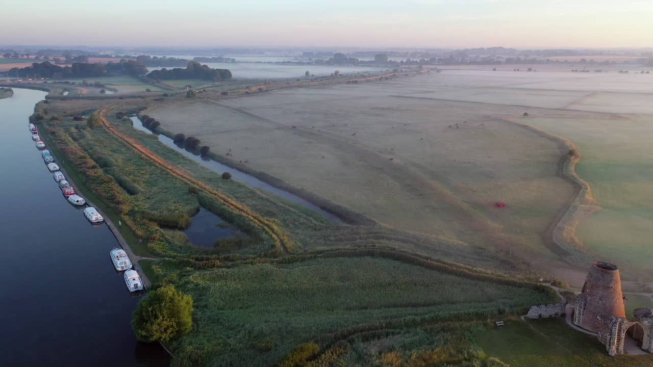 영국 노퍽에 있는 세인트 베넷의 수도원을 드러내는 일출 직후 이른 아침 안개 속에서 무인 항공기에 의해 노퍽 브로드 운하의 오른쪽에서 왼쪽으로 뒤로 비행