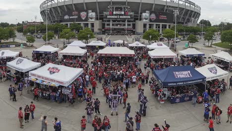 excitement builds outside the stadium: a vibrant crowd gathers in celebration for the big event under colorful tents and banners in the stadium parking lot