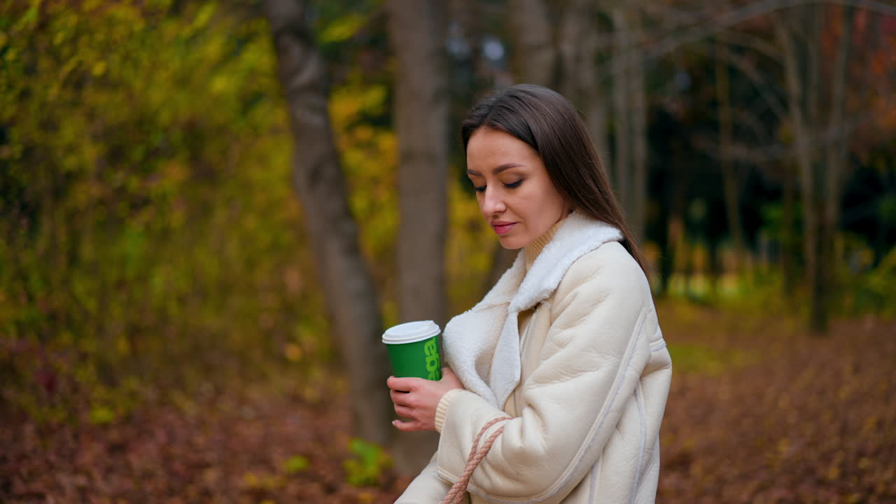 Donna che si gode un caffè al parco in autunno