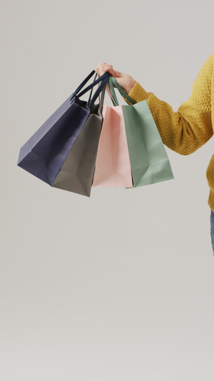 색 배경 에 쇼핑 가방 을 들고 있는 손 의 수직 비디오