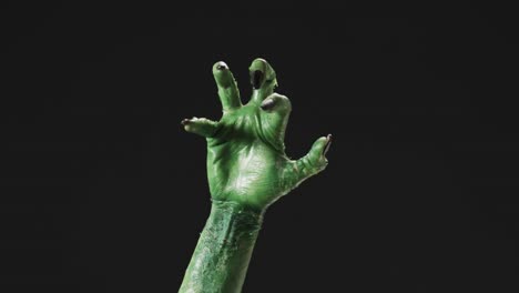 Video-of-halloween-green-monster-hand-with-copy-space-on-black-background