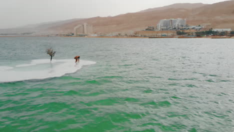 lonely-man-with-no-shirt-walking-on-a-salt-island-tree-in-the-Dead-Sea,-Israel