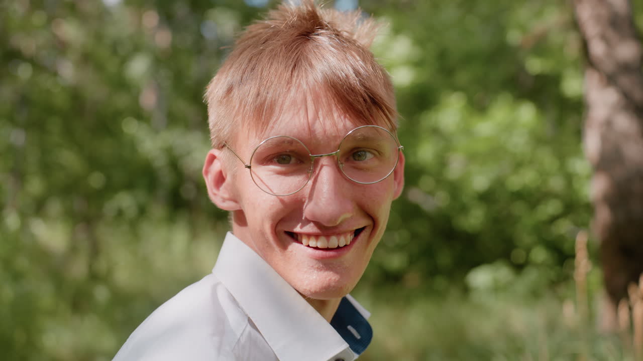 Close up back view of man in white shirt with glasses turned around in forest under daylight surrounded by green trees expressing excitement and curiosity in natural outdoor woodland environment