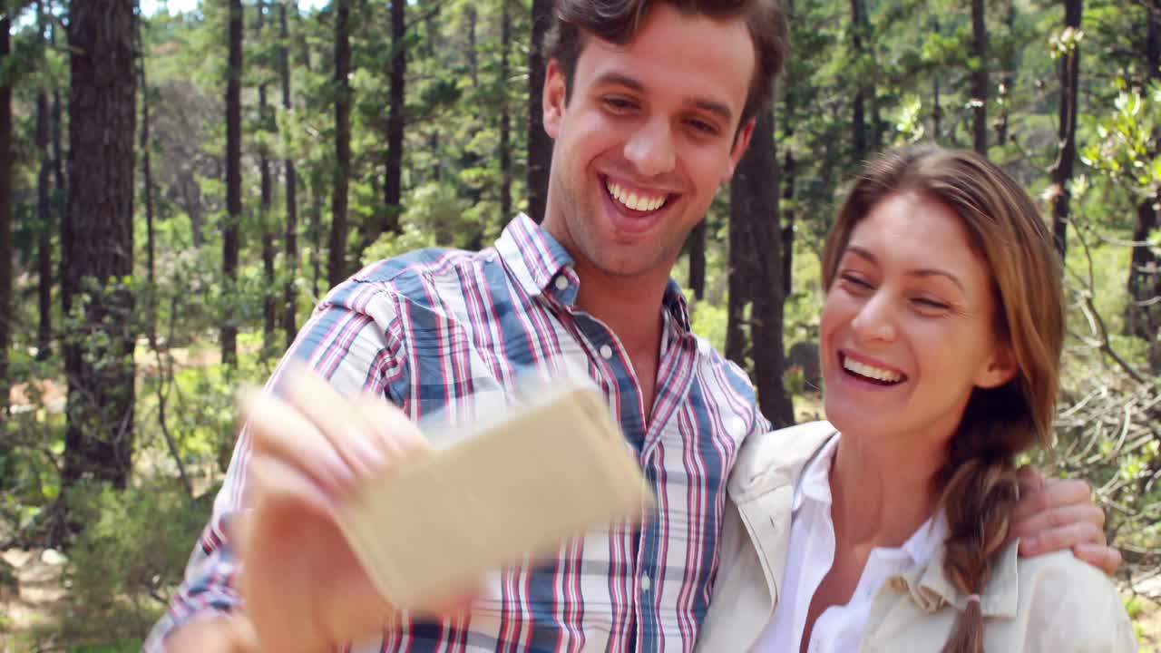 pareja sonriente en una caminata tomando una selfie