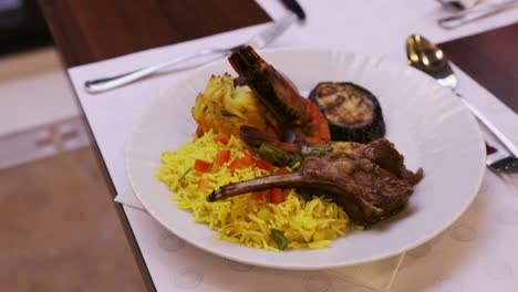 Plato-De-Arroz-Con-Azafrán-Con-Gambas,-Chuleta-De-Cordero-Y-Verduras