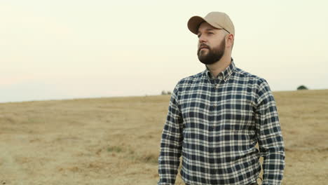 Camera-Zooming-In-The-Portrait-Of-The-Middle-Age-Farmer-In-A-Hat-Standing-And-Posing-In-The-Middle-Of-The-Field