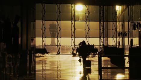 Silueta-De-Una-Chica-Caminando-Con-Maleta-En-El-Aeropuerto,-Luz-Dorada