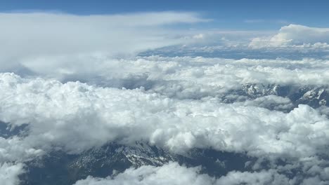 vista aérea de la cabina, punto de vista piloto, desde la cabina de un jet, de las montañas de los alpes italianos, cubiertas con algo de nieve y nubes blancas