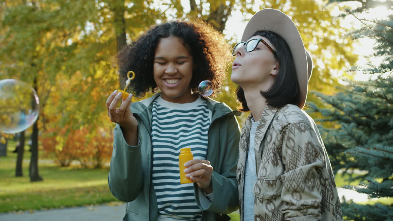 Two friends enjoying bubbles in an autumn park