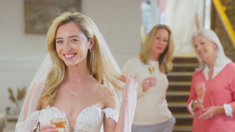 tres generaciones de mujeres de la familia beben champán hija adulta prueba su vestido de novia en la tienda de novias