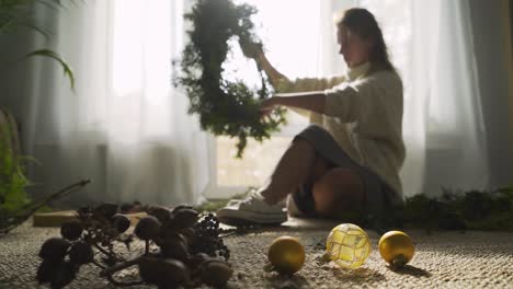 cheerful woman makes festive christmas wreath near window