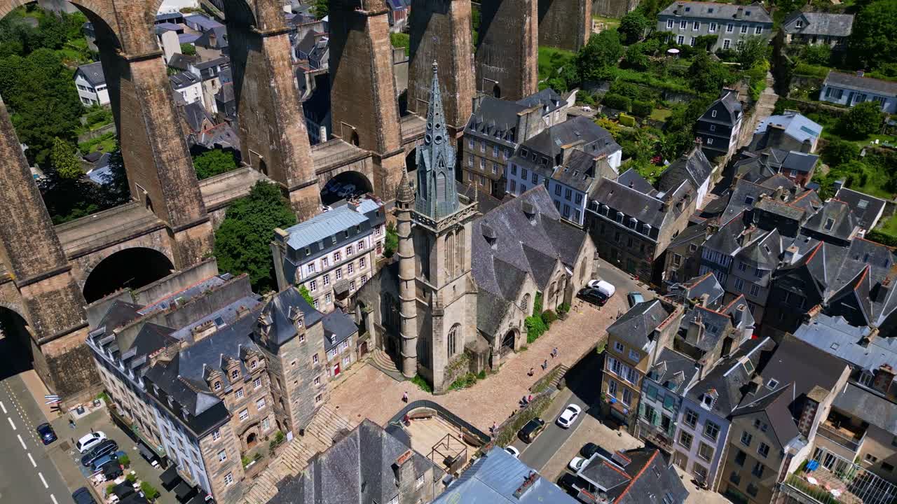Saint Melaine church, nestled below towering arches of magnificent Morlaix viaduct in Brittany, France. Aerial approach