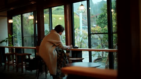 Woman writing in a cozy cafe with a view