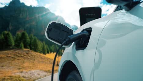 concepto de viaje progresivo en coche ev en una montaña remota con estación de carga.